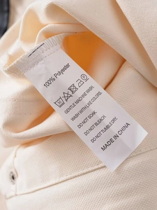 Macro view of the 100% polyester care label and washing instructions on a casual beige jacket