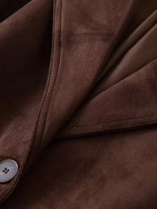 Macro shot of dark brown faux suede jacket detail showing collar stitching and a matte button