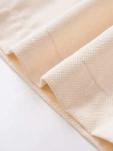 Detailed macro view of beige textile fabric with fine weave and neat stitching on edges