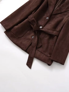 Detail of dark brown faux suede jacket featuring a notched lapel and tie-waist belt