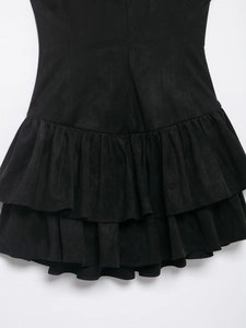 Detailed view of layered ruffle hem on a black dress with matte suede texture finish