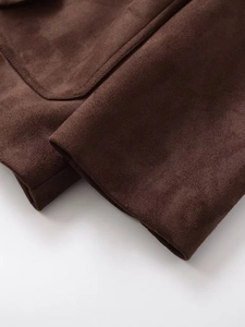 Detailed macro shot of dark brown suede fabric texture and precision stitching on jacket