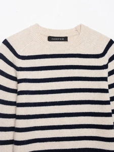 Close-up of the crew neck and classic navy striped pattern on beige knit sweater