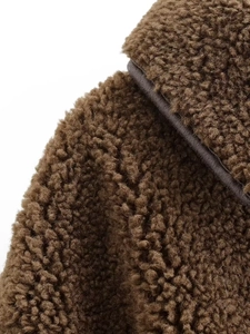 Close-up of premium brown sherpa fleece fabric showing thick curly texture and neat seams