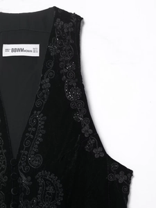 Gros plan détaillé du gilet en velours noir avec broderies de paillettes et motifs à volutes