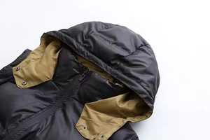 Vue détaillée du gilet à capuche noir mat avec doublure contrastée et bouton pression