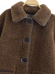 Close-up of deep brown teddy coat featuring faux fur texture and leather button details