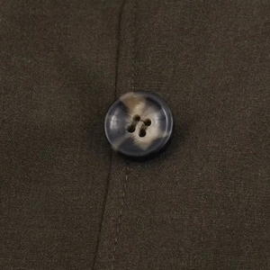 Macro shot of faux-horn button and textured fabric on short dress with lapels