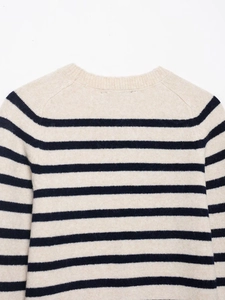 Close-up of the crew neck knit sweater with navy blue stripes on a cream background