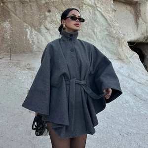 Women's dark gray wool blend cape coat with high collar and waist belt in outdoor setting