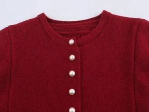 Close-up of deep red knit cardigan with elegant white pearl buttons on round neckline