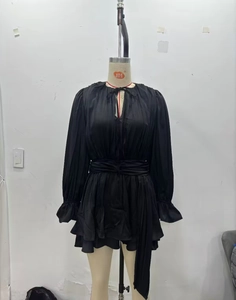 Detail of black long sleeve mini dress featuring ruched fabric and tied neckline design
