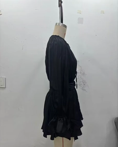 Detail view of black long sleeve mini dress featuring ruffled skirt and ruched waist details
