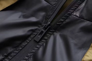 Détail de la fermeture éclair noire mate sur gilet à capuche avec tissu ripstop