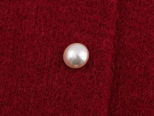 Detail of elegant pearl button on red lace-trimmed mohair knitwear cape for women