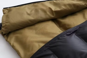 Détail du gilet à capuche montrant le tissu matelassé noir et la doublure kaki zippée