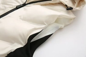 Détail de la veste matelassée blanc cassé avec fermetures éclair noires et capuchon