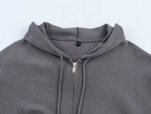 Detailed macro view of the grey ribbed hoodie neckline, metal zipper, and hood drawstring