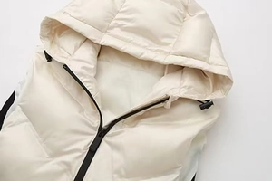 Détail du col à capuche et de la fermeture éclair sur cette veste matelassée blanc crème