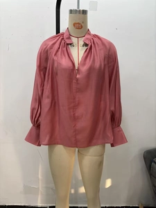 Detail of dusty pink chiffon blouse featuring pleated V-neckline and lantern sleeves