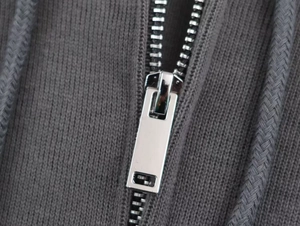 Close-up of high-quality silver metal zipper and woven drawstring on gray ribbed hoodie