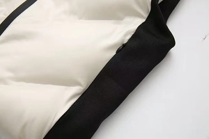 Détail du gilet à capuche bicolore avec bord-côte contrasté et fermeture éclair invisible