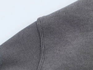 Detailed macro view of the shoulder seam on a grey ribbed knit hoodie fabric