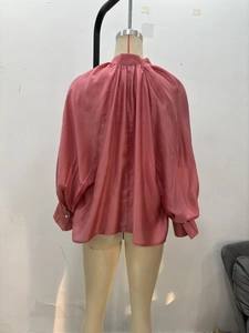 Detail of pink satin blouse back featuring deep pleats and lantern sleeves with pearl buttons