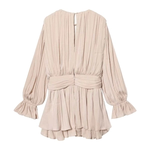 Detailed close-up of apricot long sleeve mini dress with pleated fabric and ruffled hemline