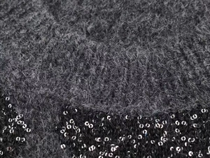 Macro detail of dark grey fuzzy mohair knit fabric with shiny silver sequin embellishments