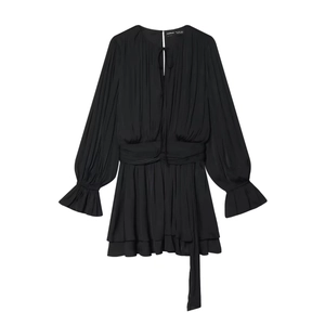 Detail of black pleated mini dress with ruched waist and ruffled bell sleeves on white background