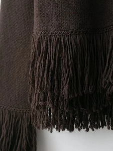 Detail of dark coffee knit cardigan featuring dense double-layered long fringe hemline