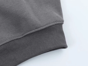 Detail of ribbed cuffs on a dark grey knit hoodie with high quality stitching