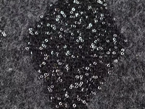 Close-up of fluffy dark grey knit fabric with shimmering silver sequins detailing