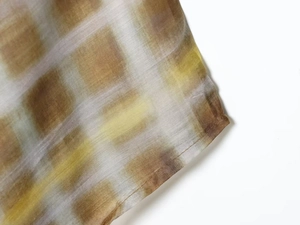 Close-up of brown plaid fabric with gradient pattern and fine rolled hem stitching
