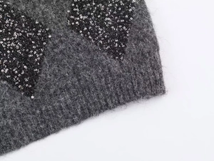 Detail of dark grey fuzzy knit sweater with shimmering black sequin heart pattern