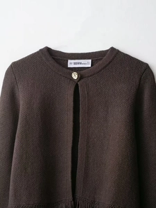 Detail of round neck and gold embossed button on a dark brown knit cardigan jacket