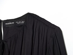 Detailed view of black pleated dress neckline featuring the internal size and brand label