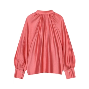 Detail of coral satin blouse showing high pleated neckline and lantern sleeves with pearl cuffs