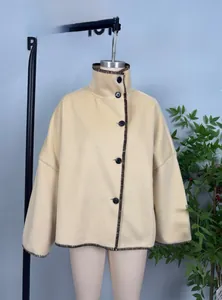 Detail of light beige cape coat featuring standing collar and contrast blanket stitching
