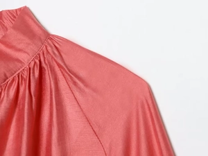 Detailed view of coral silk-satin fabric with elegant pleated collar and shoulder stitching