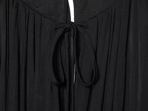 Detail of neckline tie knot and gathered pleats on black long sleeve mini dress