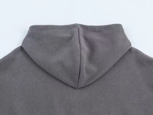 Detailed close-up of dark grey ribbed knit fabric and hood stitching on this hoodie