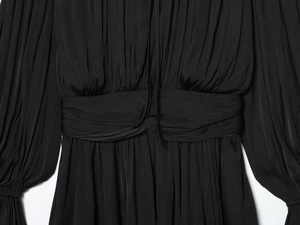 Detail of waist pleats and smocked cuffs on a black long sleeve mini dress