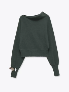 Detail of dark green off-shoulder sweater with silver metal ring on the wide ribbed cuff