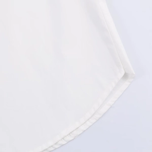 Detail of the curved hemline with precise double-needle stitching on white poplin fabric
