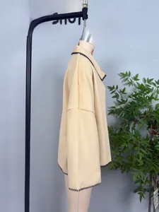 Detail of beige wool coat with dark contrast whipstitch embroidery on collar and cuffs