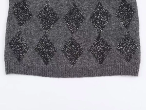 Detail of dark gray fluffy knit sweater with black sequins in argyle pattern