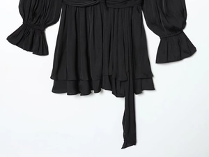 Macro detail of black satin long sleeve dress with ruffles and glossy pleated texture