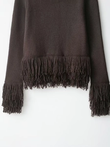 Detailed view of long tassels on dark brown knit jacket with intricate stitching details